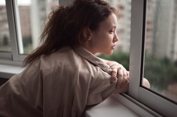 Woman looking out a window with cityscape in background