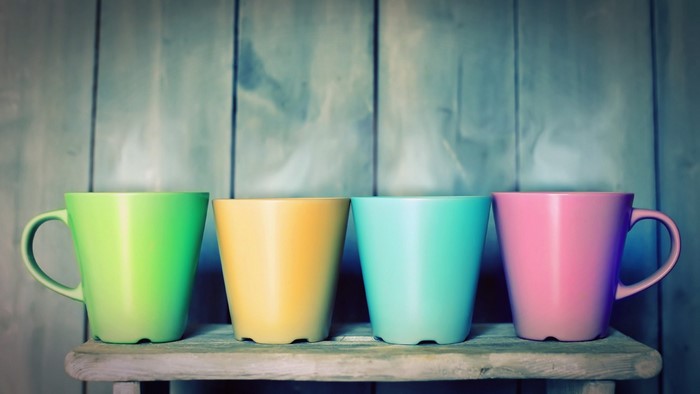 Four colorful mugs on a wooden shelf