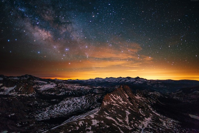 Milky Way galaxy over snow-capped mountains at dusk