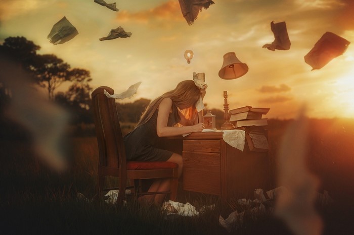 Woman writing at a desk outdoors with floating objects