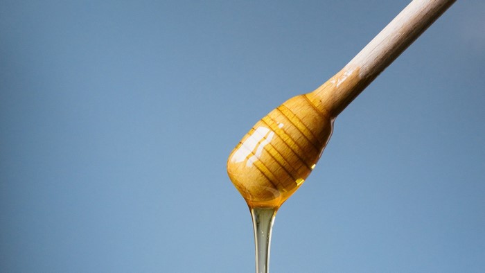 Honey dripping from a wooden honey dipper