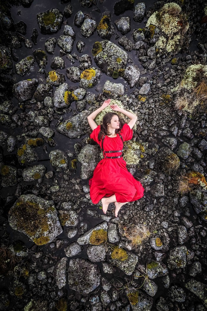Woman in red dress lying on rocks