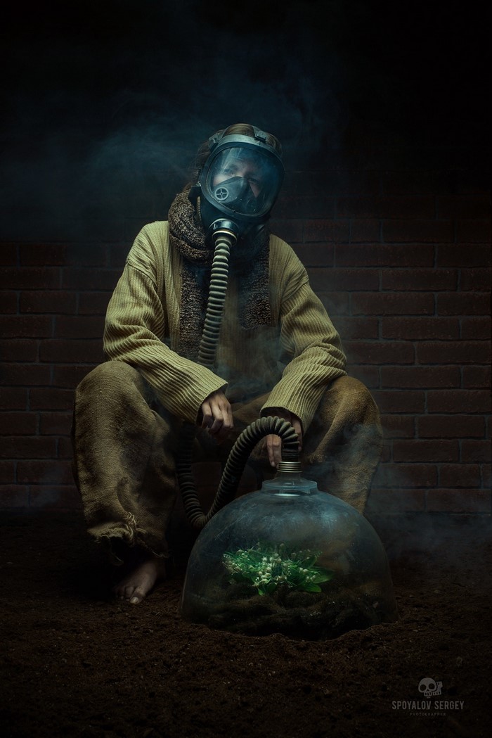 Man in gas mask with plant under glass dome