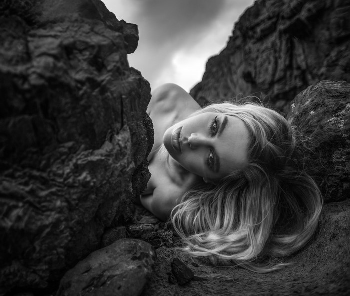 Monochrome portrait of a woman lying on rocks