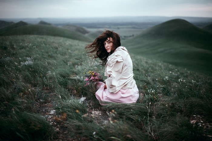 Woman with flowers in a grassy landscape