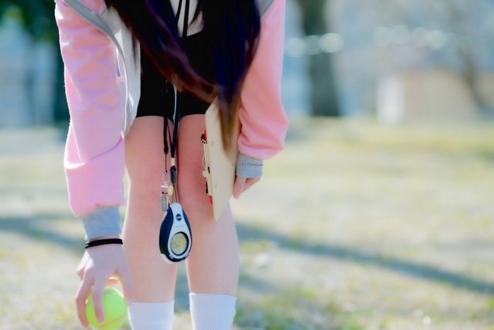 Girl in pink jacket holding tennis ball and clipboard