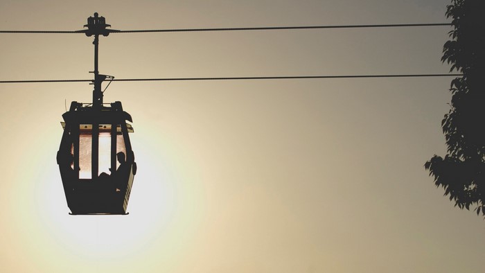 Silhouette of a cable car with people reading