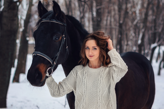 Woman in sweater with horse in winter forest