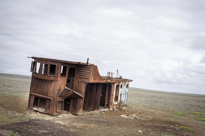 Rusty shipwreck on a dry, desolate landscape