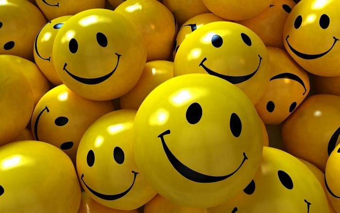 A pile of yellow smiley face balloons