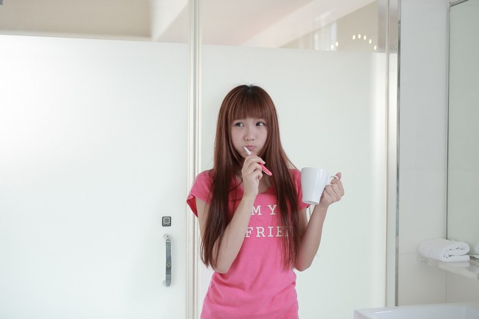 Woman brushing teeth with a mug