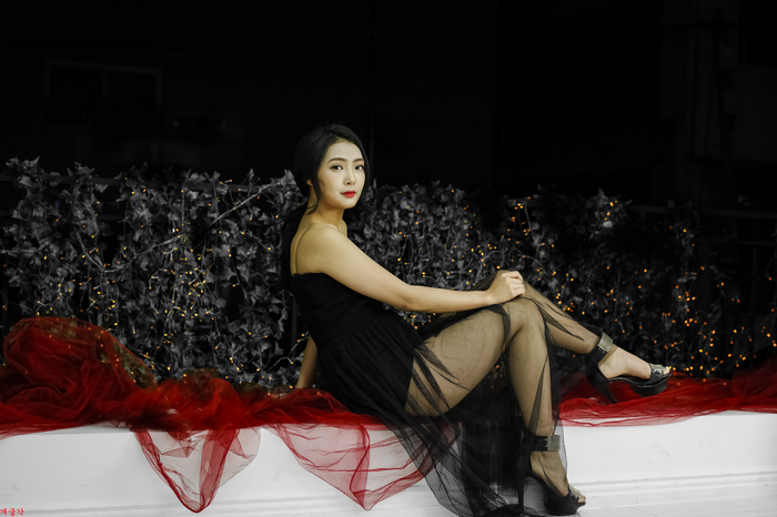 Asian woman in black dress posing with red fabric