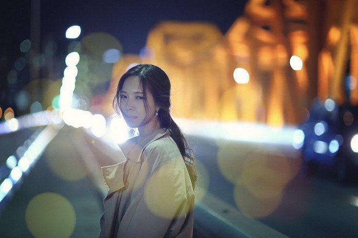 Asian woman posing on a bridge at night