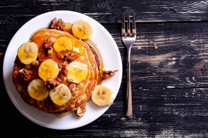 Pancakes with bananas, walnuts, and syrup on a plate