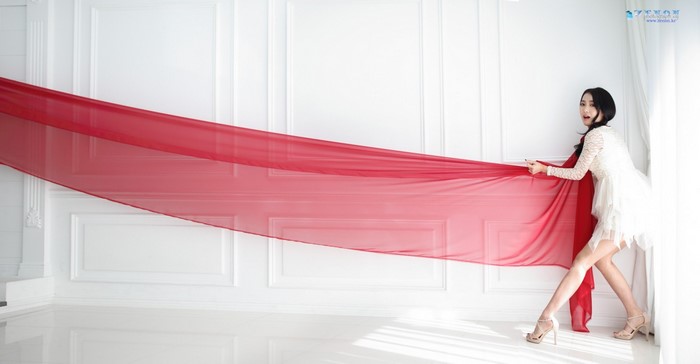 Asian woman in white dress holding red fabric