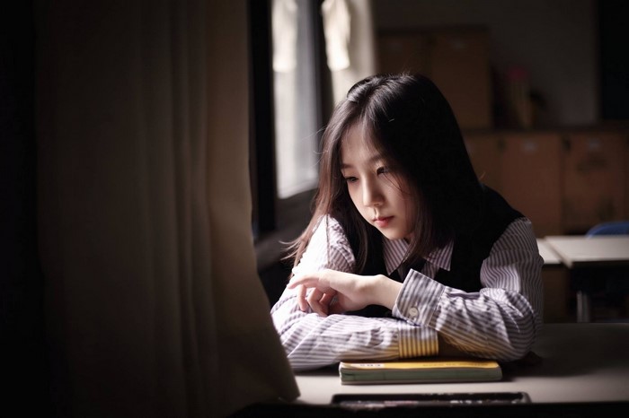 Young Asian girl in school uniform looking down