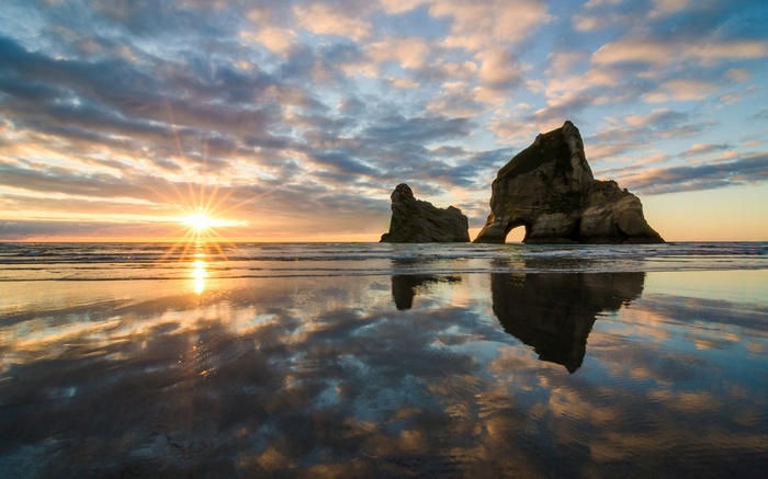 Sunset over ocean with rock formations and reflection