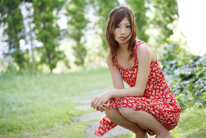 Yoko Ogura squatting in a red dress outdoors