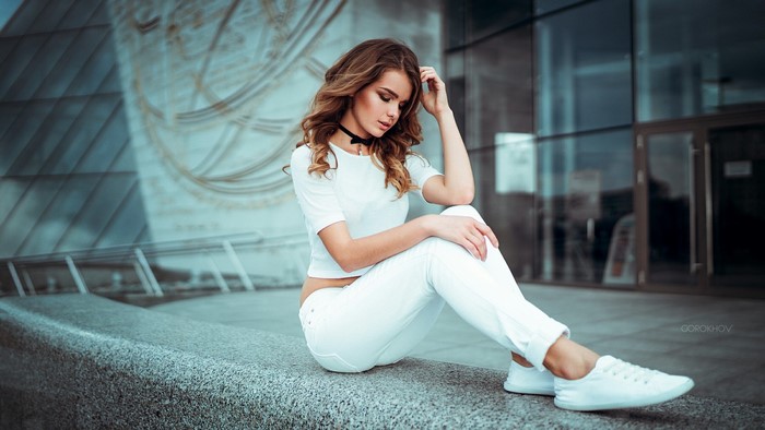 Woman in white clothing sitting outdoors