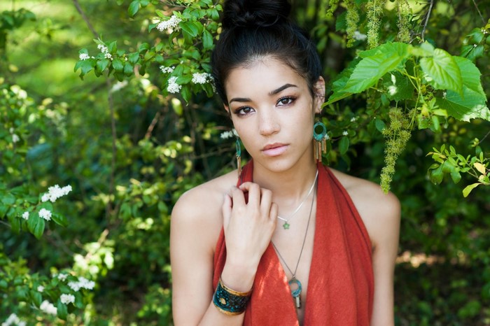 Woman with hair bun and red halter top in nature