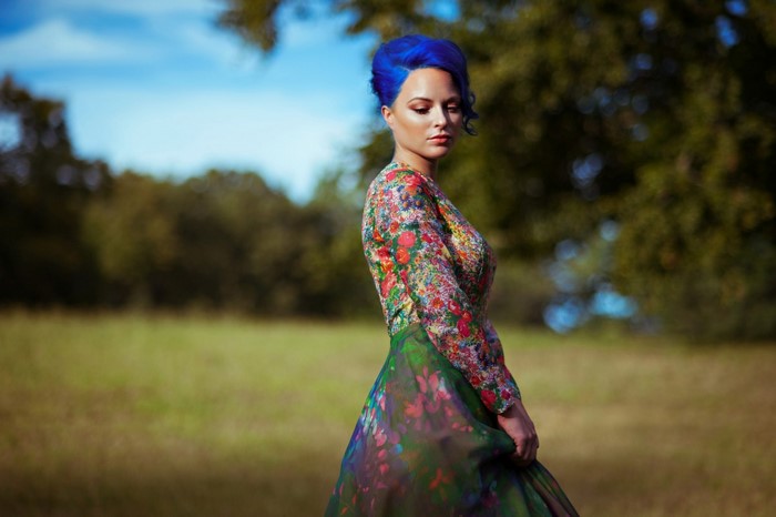 Woman with blue hair in a floral dress outdoors
