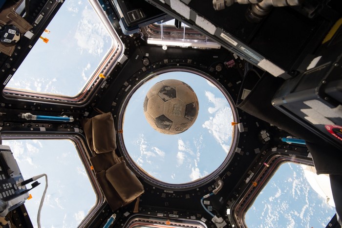 Soccer ball floating in front of Earth from International Space Station window