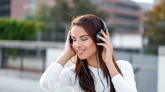 Woman wearing headphones listening to music outdoors