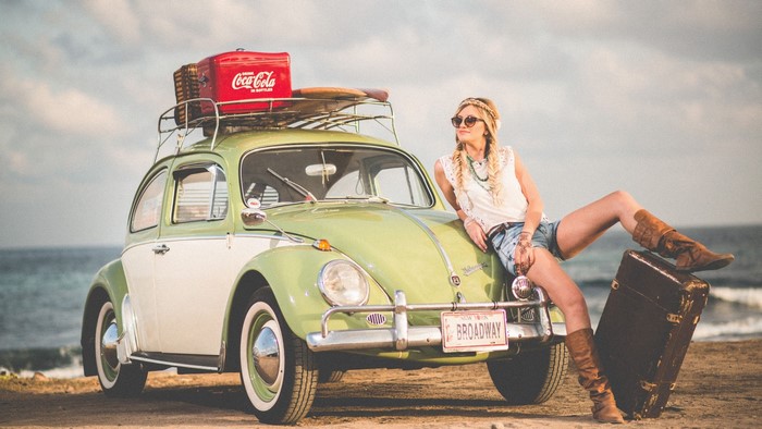 Woman with vintage Volkswagen Beetle and Coca-Cola cooler