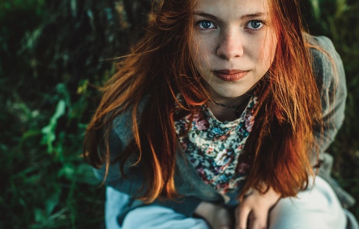 Young woman with red hair and blue eyes looking up