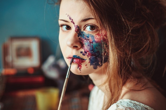 Woman with face paint applying makeup with a brush