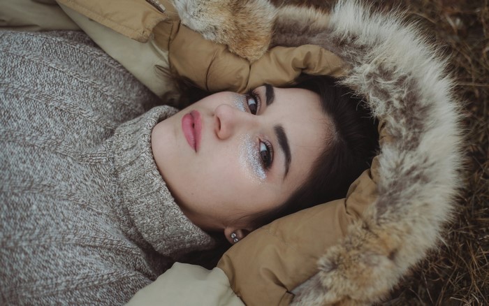 Woman with glitter makeup lying on her back