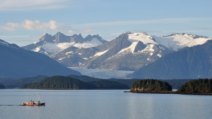 Boat on water with snow-capped mountains and glacier in Alaska