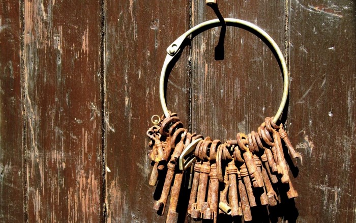 Rusty keys hanging on a hook against a wooden door