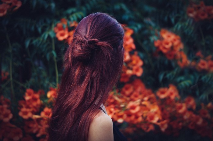 Woman with red hair in front of orange flowers