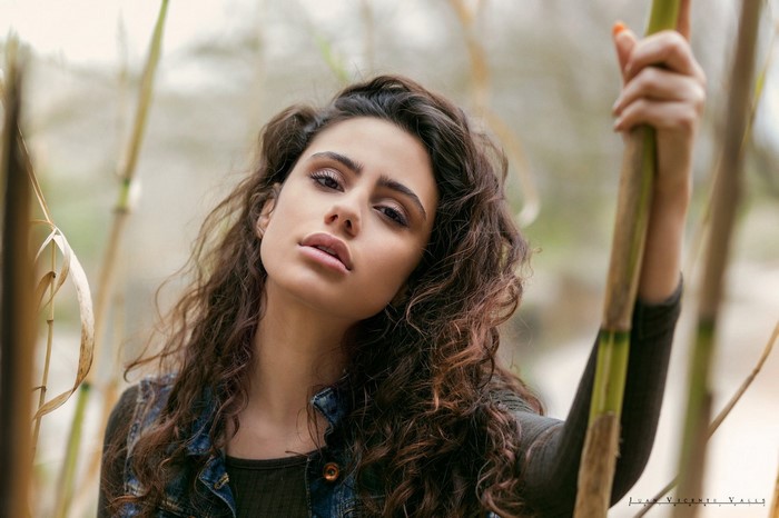 Woman with curly brown hair holding a plant stalk