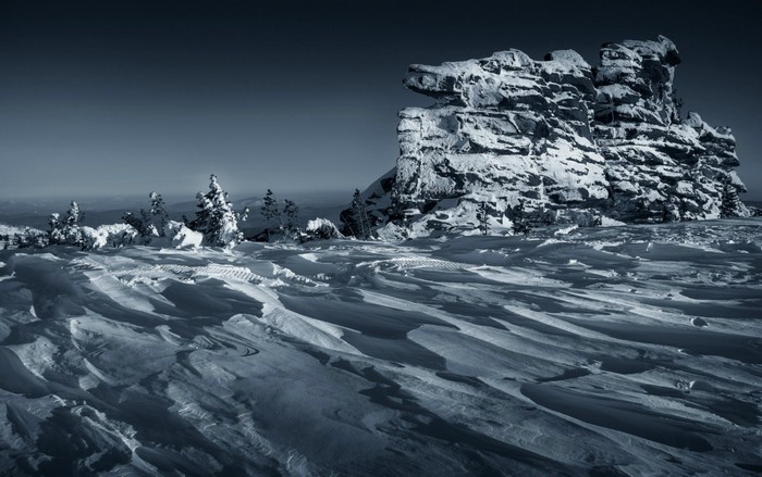 Snowy mountain landscape with rock formations and trees