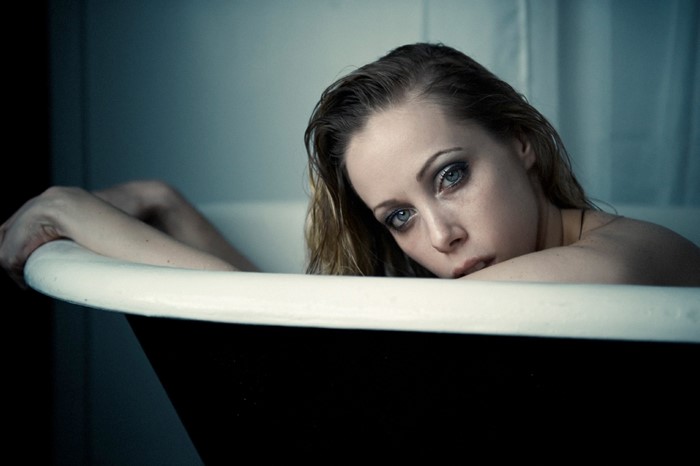 Woman in bathtub with dramatic makeup