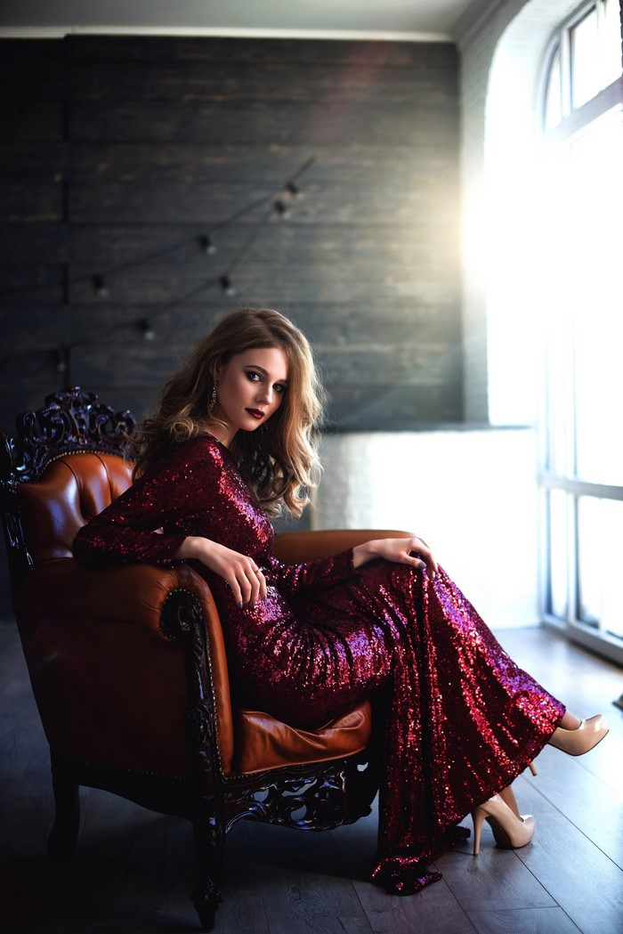 Woman in sequined dress sitting in a leather chair