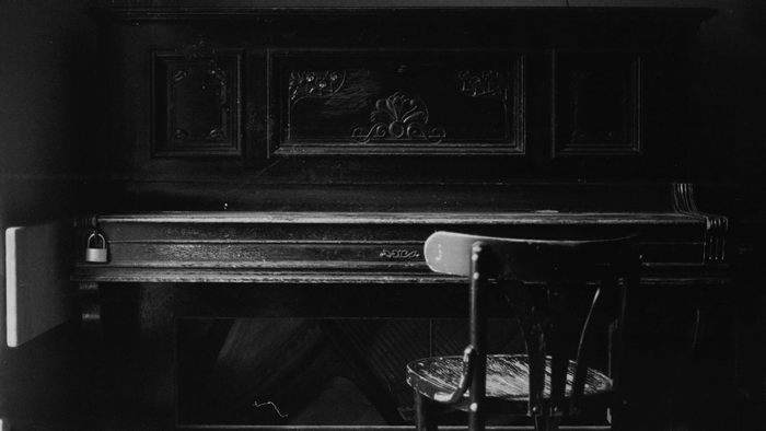 Old piano with a chair and a lock
