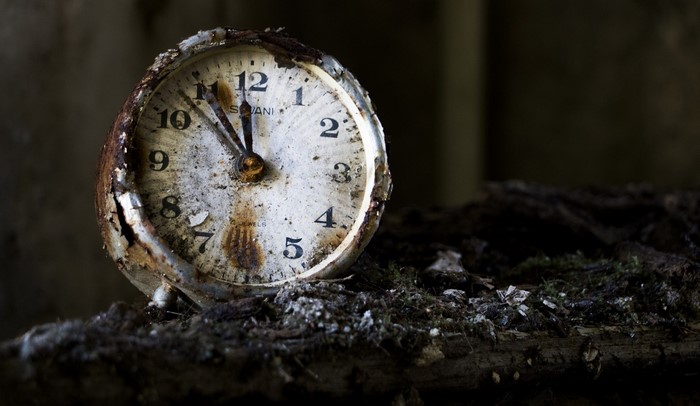 Close up of a rusty old clock on wood
