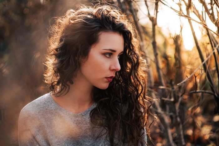 Woman with curly brown hair in sunlight