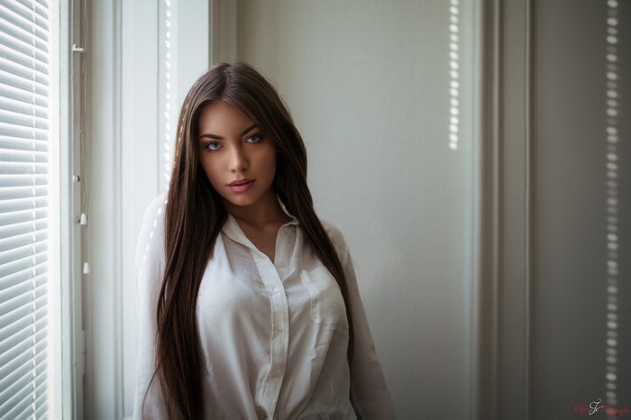 Woman with long brown hair wearing a white shirt