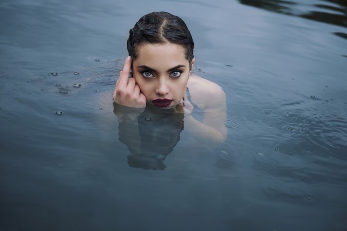 Woman with blue eyes and red lipstick in water