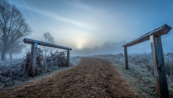 Misty winter morning with a dirt path and wooden gates