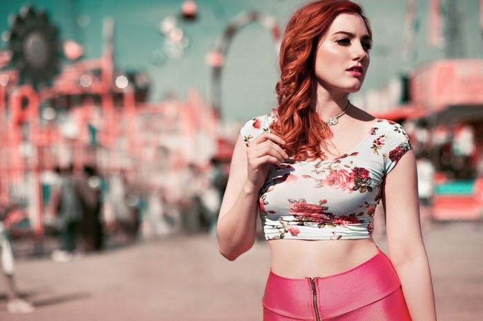 Redhead woman in floral top and pink pants at amusement park