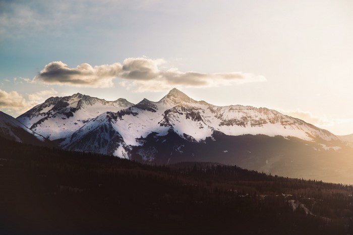 Snow-capped mountains at sunset with clouds