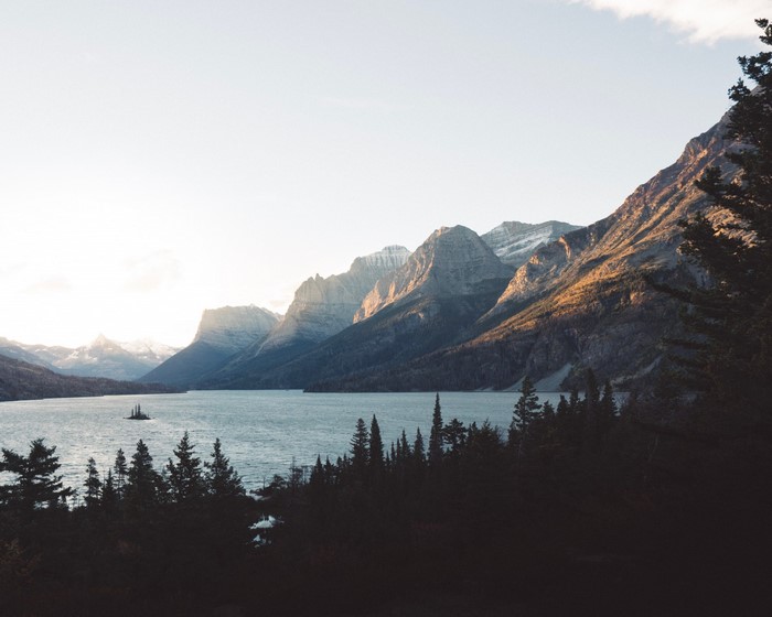 Lake and mountains at sunrise with trees in foreground