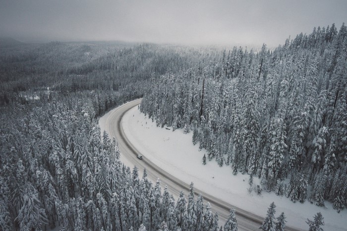 Car driving on a snowy road through a winter forest