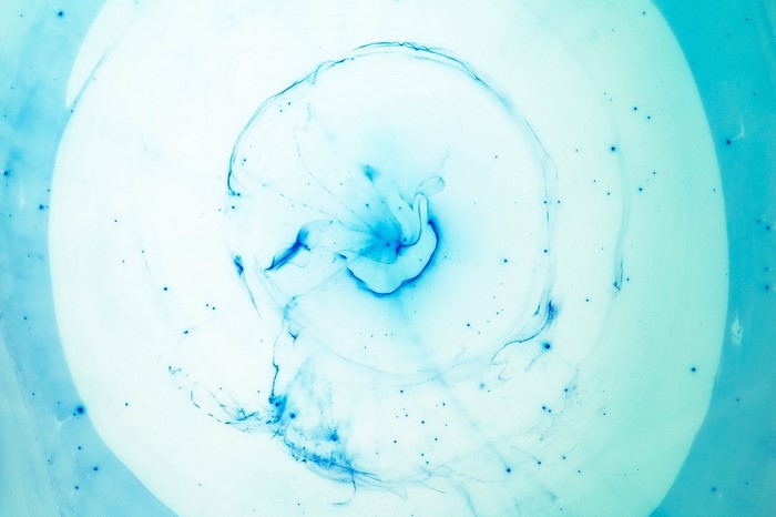 Blue ink swirling in water with small particles