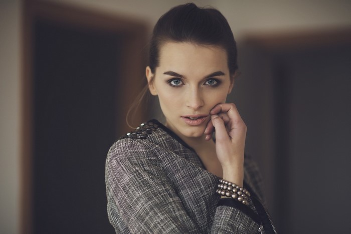 Woman with hand on face, wearing a patterned jacket